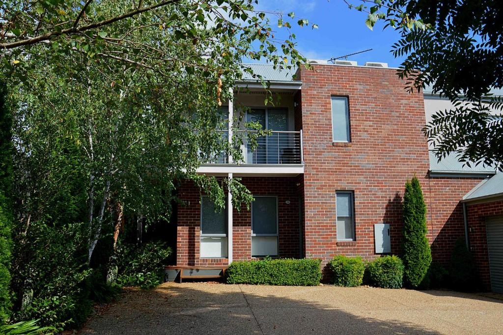 a red brick house with a window and bushes at The Track - beautiful townhouse in Bright in Bright