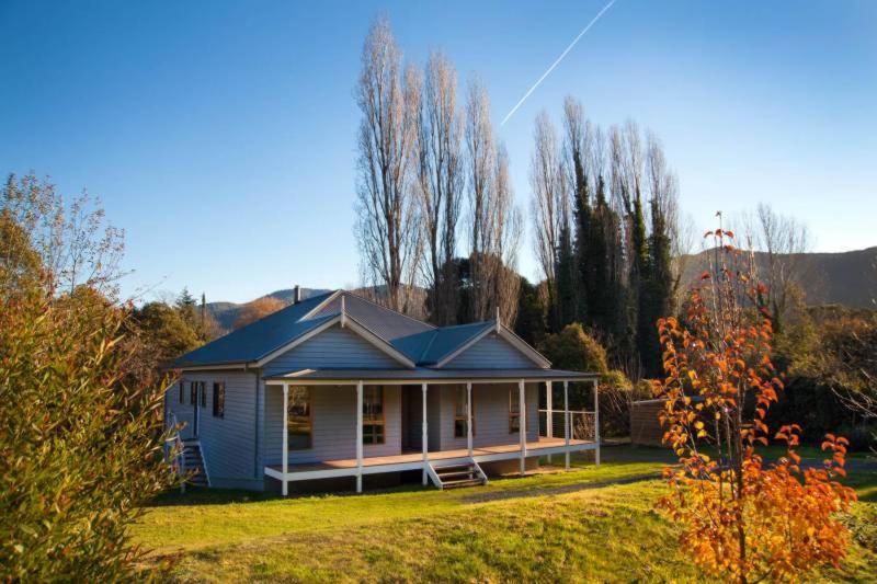 a white house with a blue roof on a yard at Growlers Creek Lodge in Wandiligong