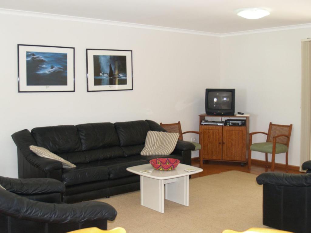 a living room with a black couch and a table at Rocky Beach Cottage 26 Pacific Drive in Port Macquarie