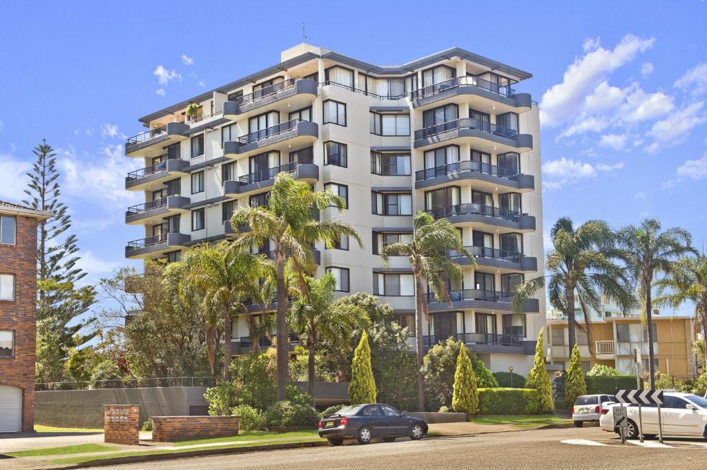 a tall white apartment building with palm trees at Sundial 602 8-10 Hollingworth Street in Port Macquarie