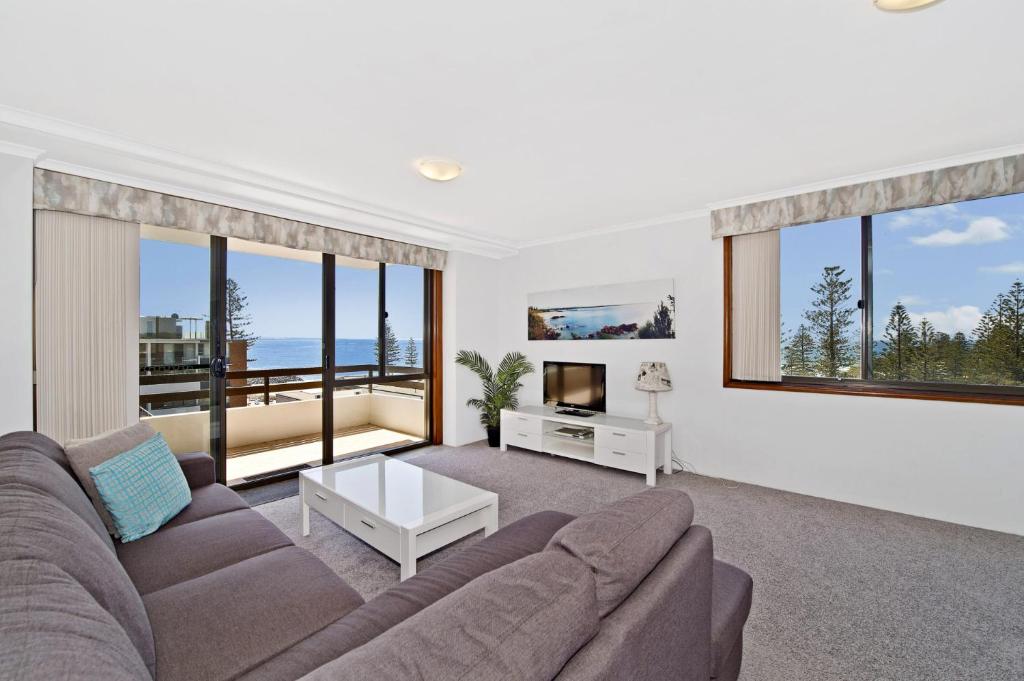 a living room with a couch and a tv and windows at Akuna 18 6 Joffre Street in Port Macquarie