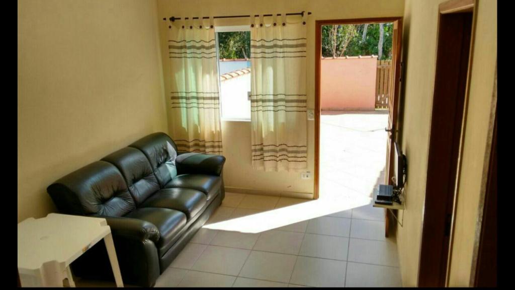 a living room with a leather couch and a sliding glass door at Casas em Boracéia in Boracéia