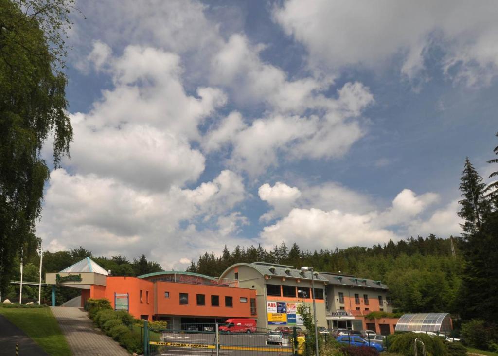 ein Parkplatz mit einem Gebäude und einem wolkigen Himmel in der Unterkunft Hotel Břízky in Jablonec nad Nisou