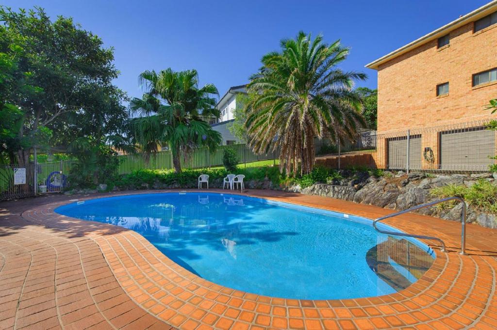 a swimming pool with two chairs next to a house at Shelly Cove 13 113 Pacific Drive in Port Macquarie