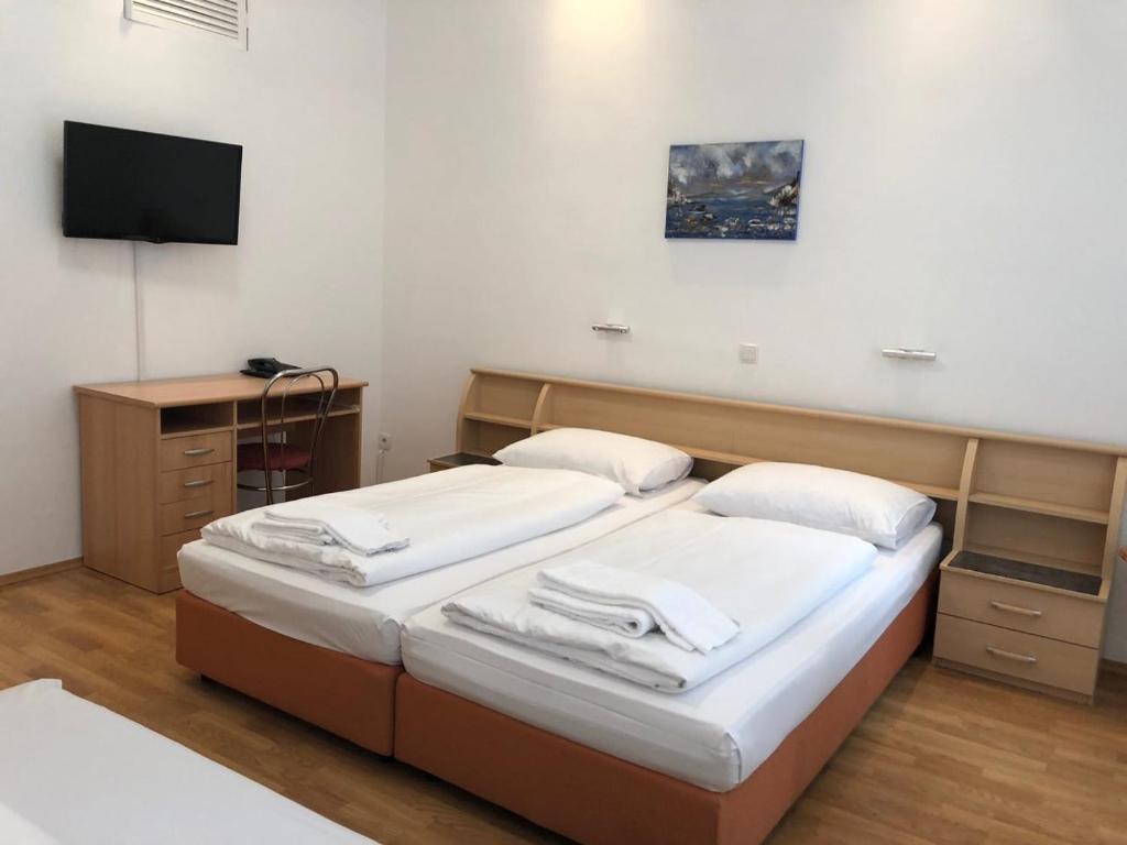 a room with two beds and a tv on the wall at Pension Vera in Vienna