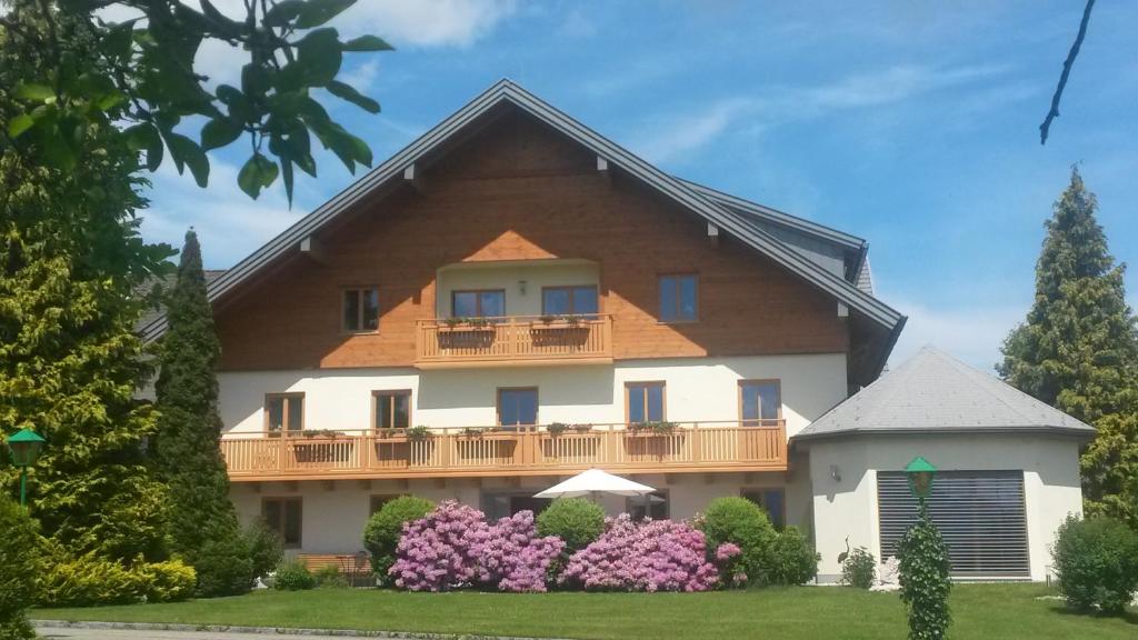 ein großes Haus mit einem Balkon und Blumen in der Unterkunft Pension Kreuzinger, 5310 Tiefgraben in Mondsee