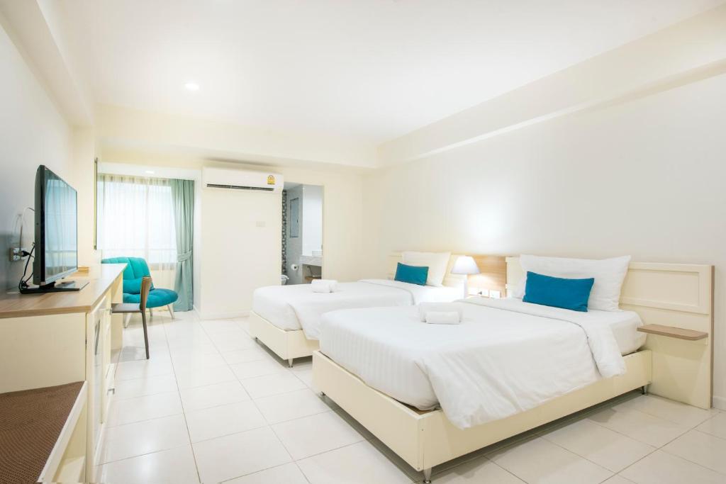 A bright twin room with two beds, a television, desk and balcony doorway.