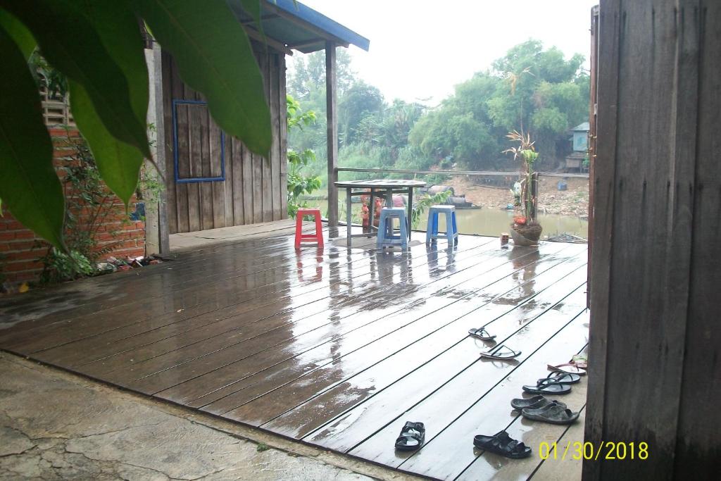 una terraza de madera con chanclas y un parque infantil en Wooden House, en Battambang