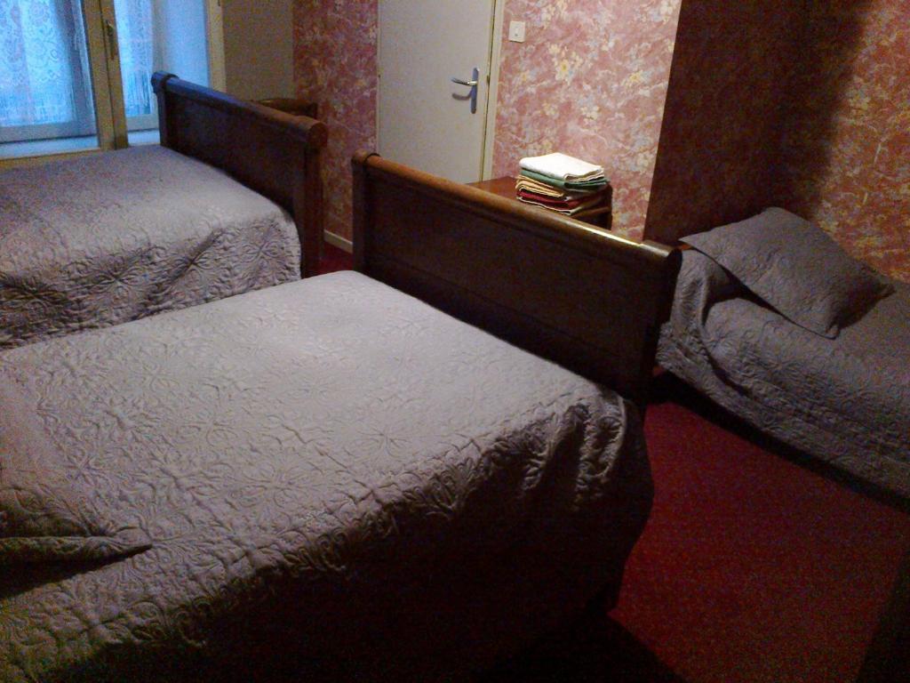 a hotel room with two beds and a chair at Le Commerce in Bulgnéville