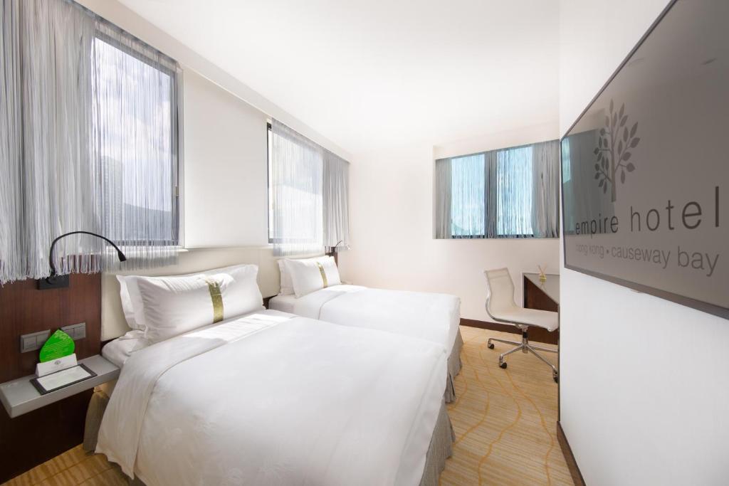 Habitación de hotel con cama blanca grande y escritorio. en Empire Hotel Causeway Bay, en Hong Kong