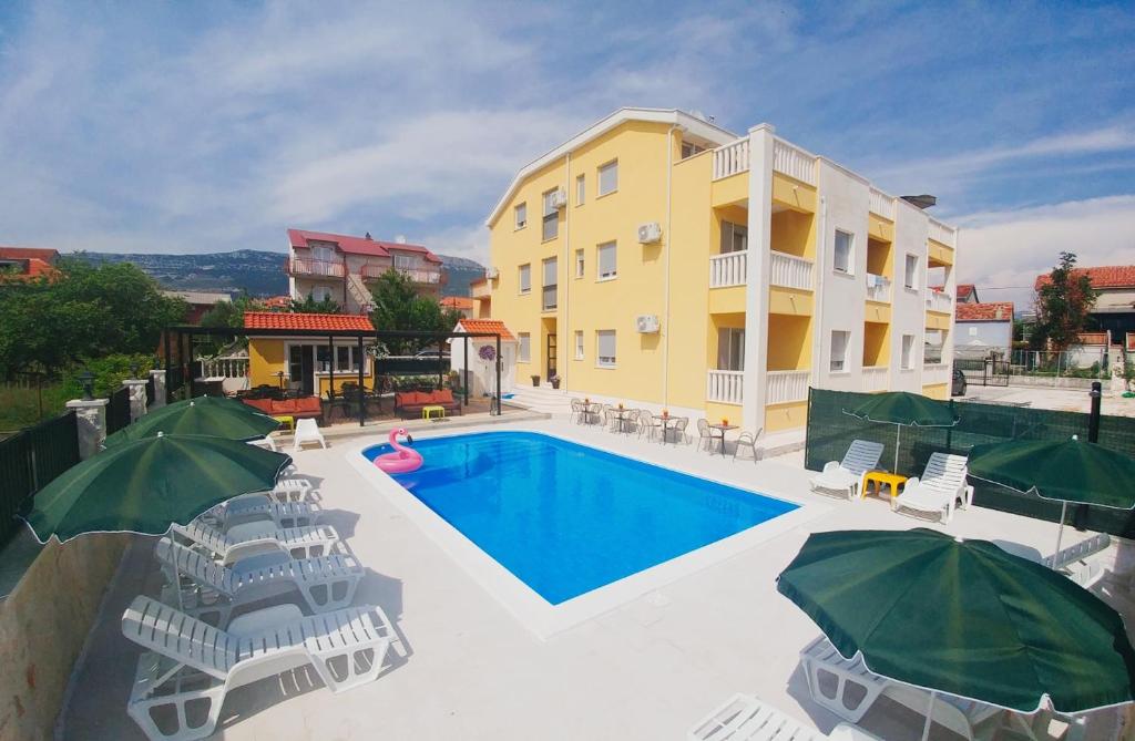 - une piscine avec des chaises et des parasols à côté d'un bâtiment dans l'établissement Villa Iva-Dom, à Kaštela