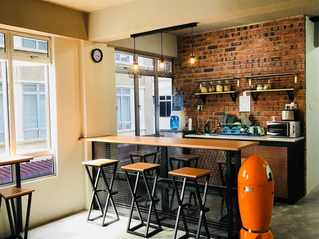 a kitchen with a counter and some stools at The Good Travelers Hostel - KL Airport in Sepang