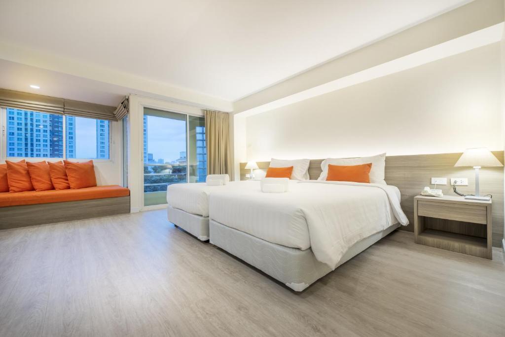 A bright bedroom with twin beds, a cushioned window seat and a city-facing corner window.