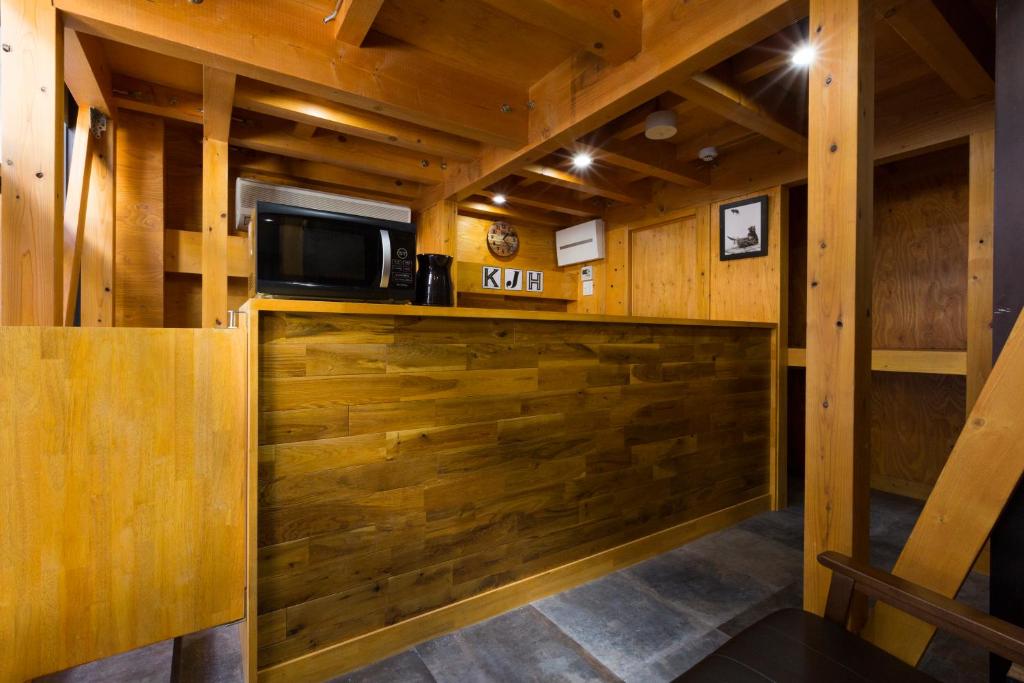 Apartament obejmuje kuchnię z drewnianymi ścianami oraz bar z kuchenką mikrofalową. w obiekcie ゲストハウス高円寺純情ホテル -Guest House Koenji Junjo Hotel- w Tokio
