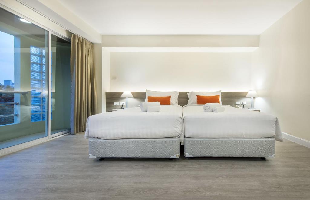 A straightforward twin room with two beds beside a large glazed opening.