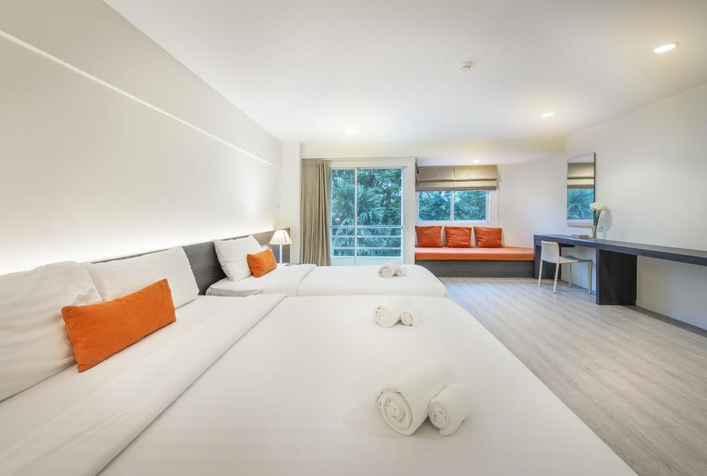 A bedroom with two beds, a long desk and a window-side bench.