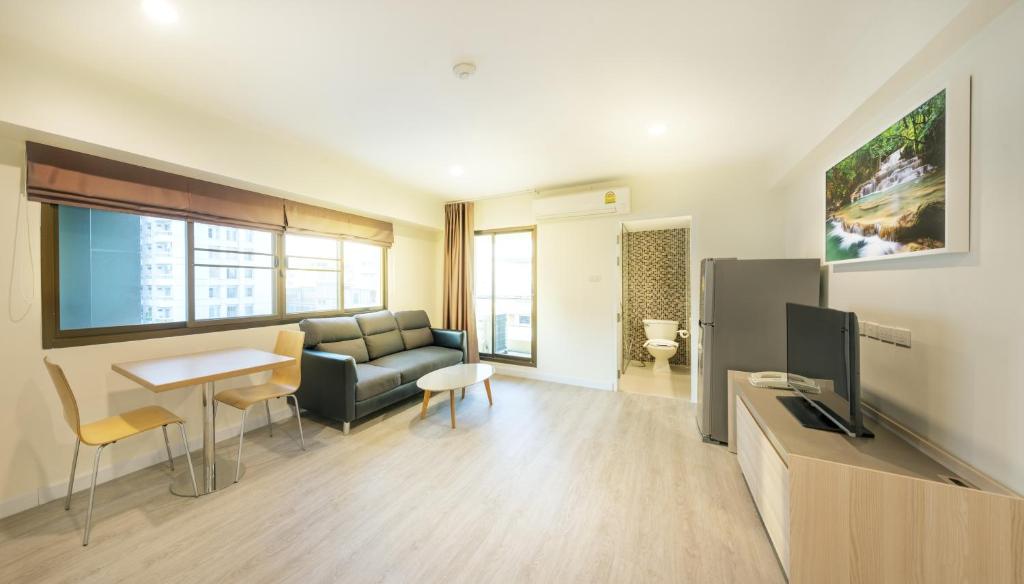 A spacious living area with a sofa, dining table, television and visible bathroom entrance.