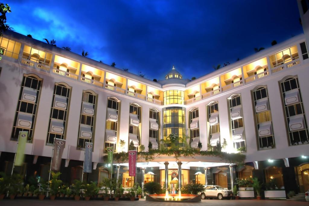 a large white building with a car parked in front at Sandesh The Prince in Mysore