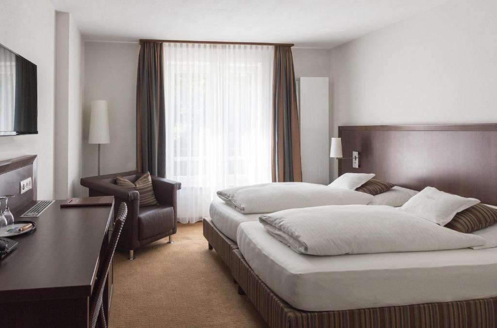 a hotel room with two beds and a desk at Restaurant & Hotel Engelkeller in Memmingen