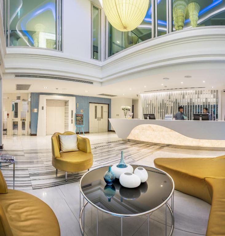 A polished lobby lounge with sculptural reception furniture, yellow seating and decorative lighting.