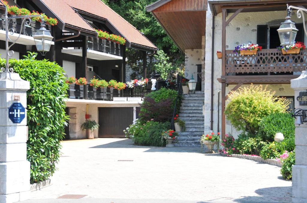 un bâtiment avec des boîtes de fleurs sur ses balcons dans l'établissement Auberge Du Roselet, à Duingt