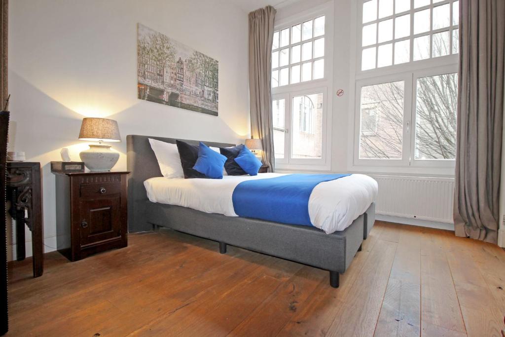 a bedroom with a large bed with blue and white sheets at New monumental garden view Studio in Amsterdam