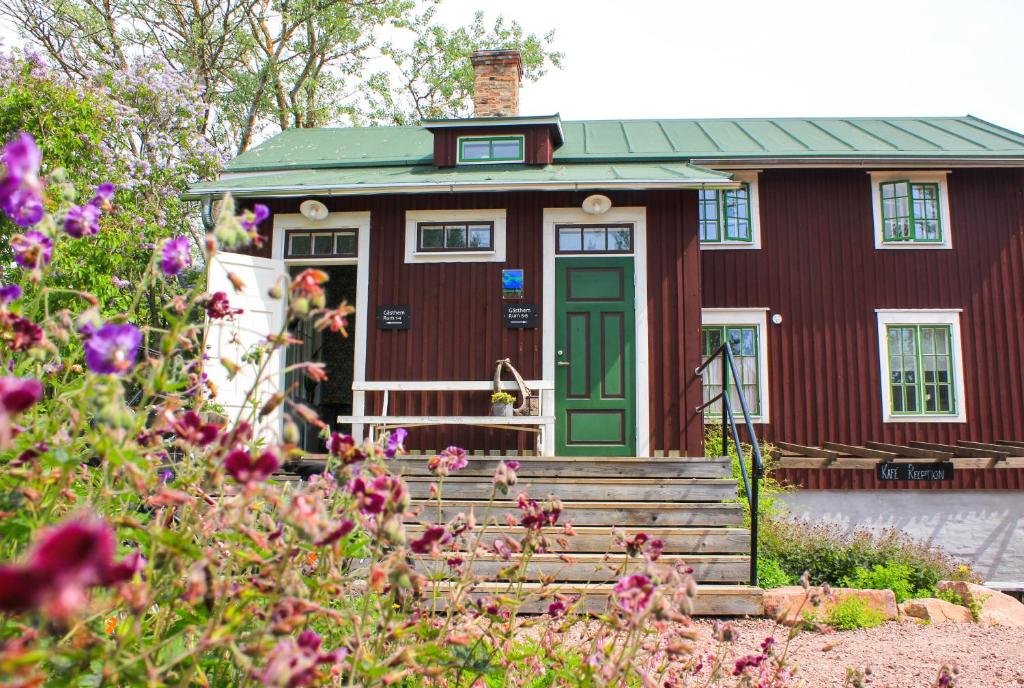 a red house with a green door and some flowers at Brobacka Gästhem in Jomala