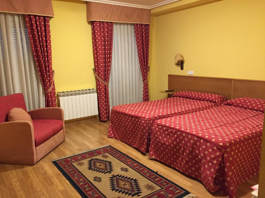 a hotel room with two beds and a chair at Hotel Benlloch in Salas de los Infantes