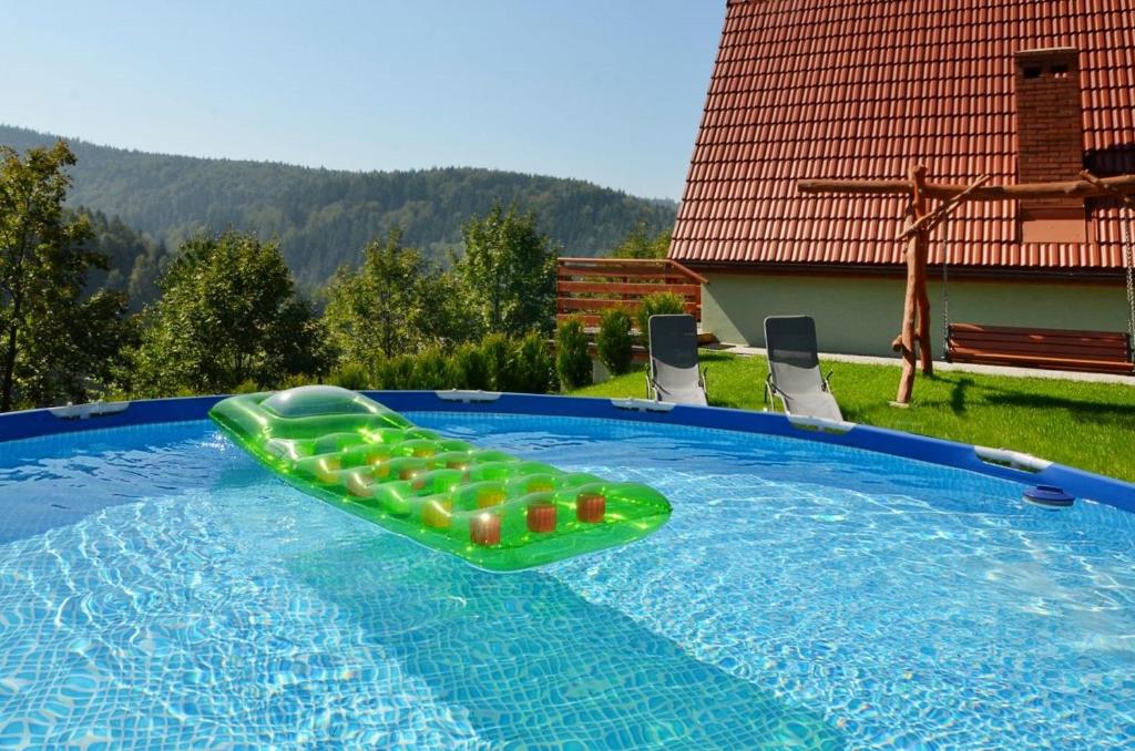 a swimming pool with a green inflatable raft in it at Domki Beskid in Rzyki