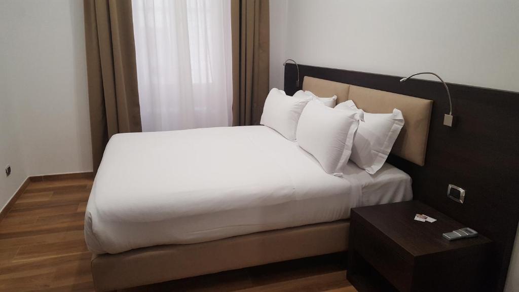ローマにあるUna Finestra su Montiのテーブル付きのホテルルームの白いベッド