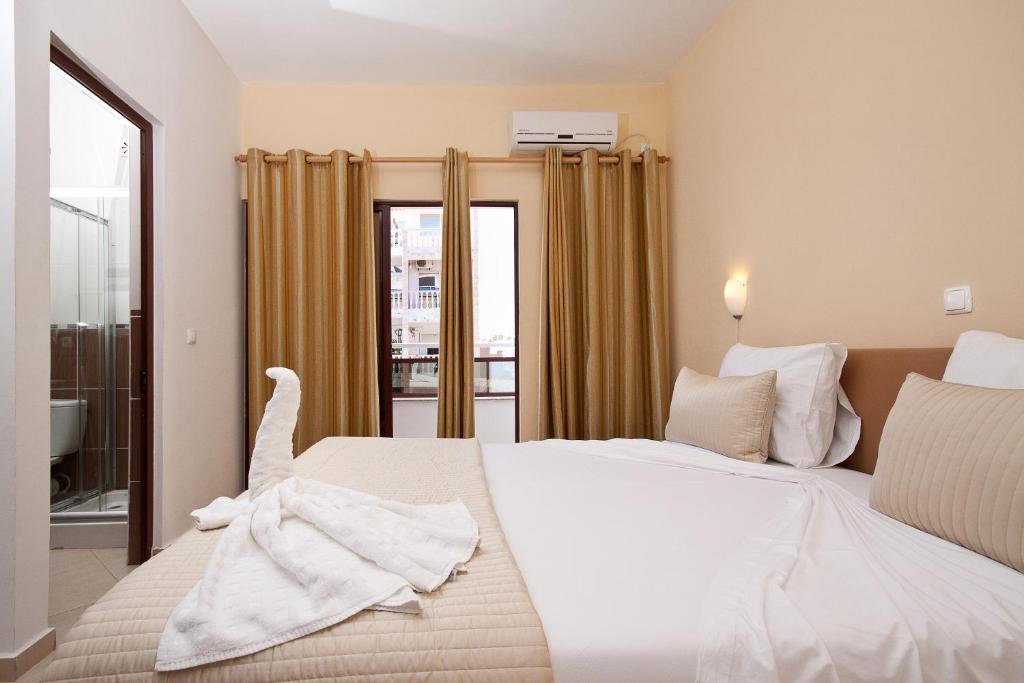 a bedroom with a large white bed and a window at Aparthotel Praiano in Praia