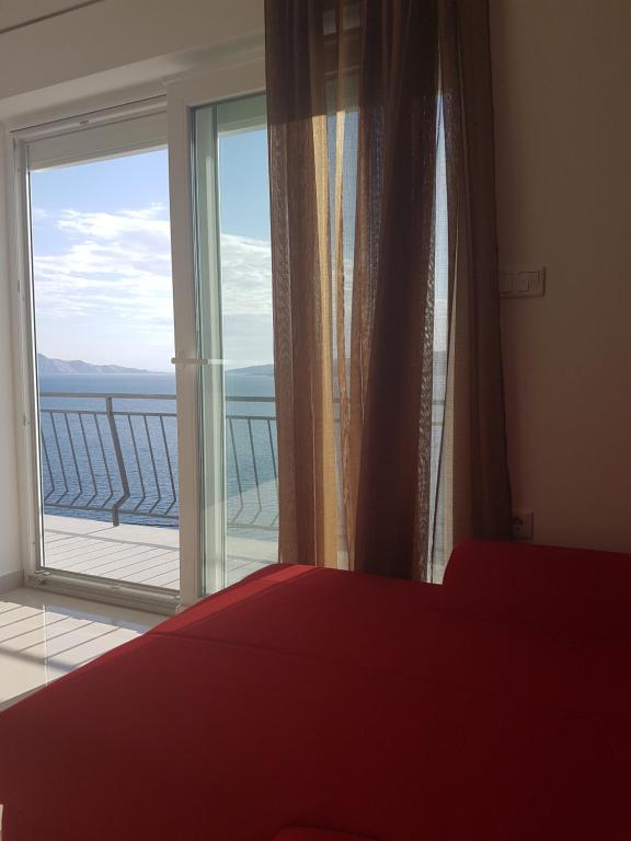 a bedroom with a red bed and a large window at Apartments Tereza in Senj