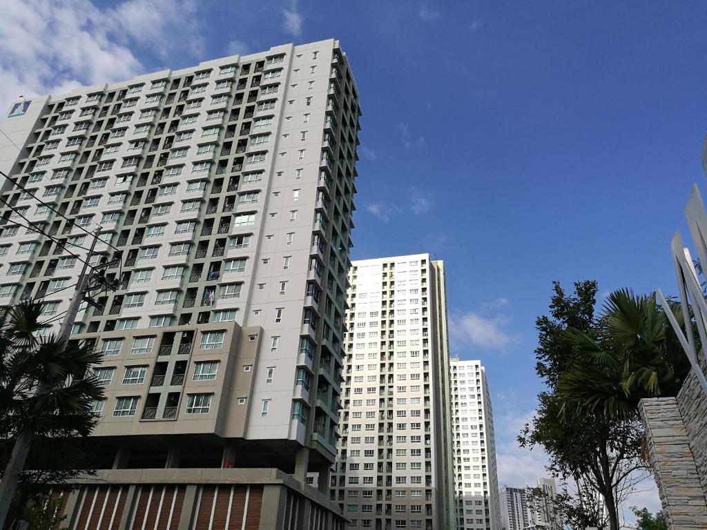 a tall white building with palm trees in front of it at Lumpini Vacation Apartment in Pattaya North