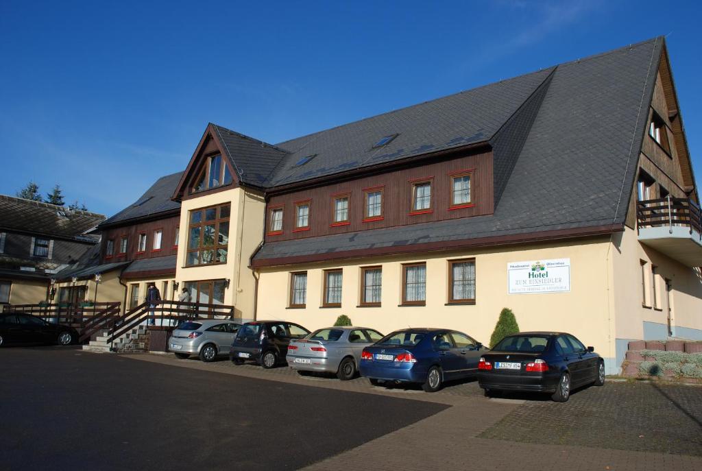 ein großes Gebäude mit davor geparkt in der Unterkunft Hotel "Zum Einsiedler" in Deutschneudorf