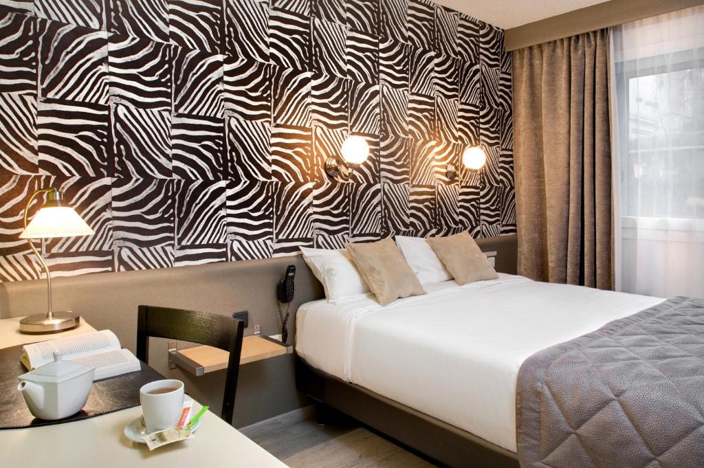 Ένα ή περισσότερα κρεβάτια σε δωμάτιο στο Logis Hôtel du Midi - Saint Etienne Sud