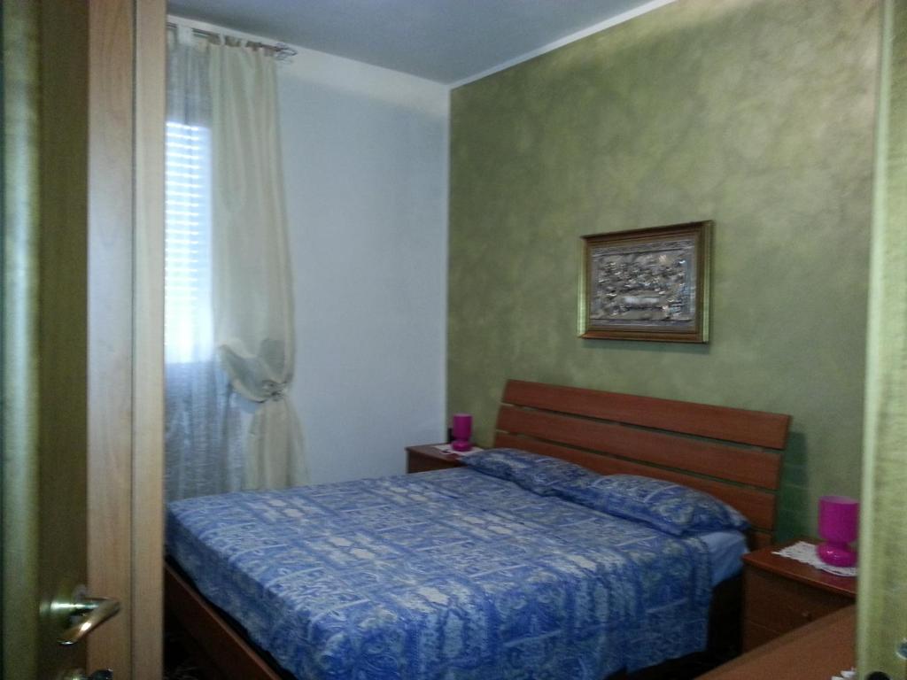 Un dormitorio con una cama azul y una ventana en La via per Milano, en Vigevano