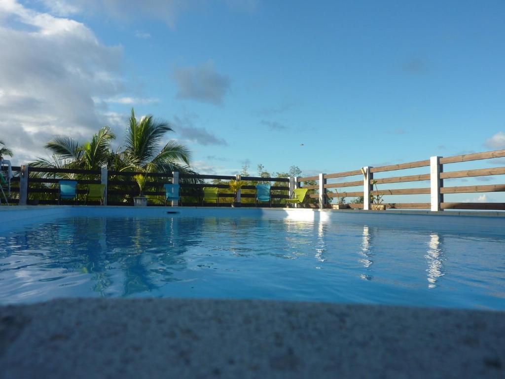 une grande piscine avec une clôture et des palmiers dans l'établissement La Pointe au Corail, à Sainte-Rose