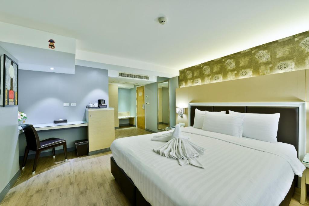 a hotel room with a large bed and a desk at Prestige Suites Nana in Bangkok