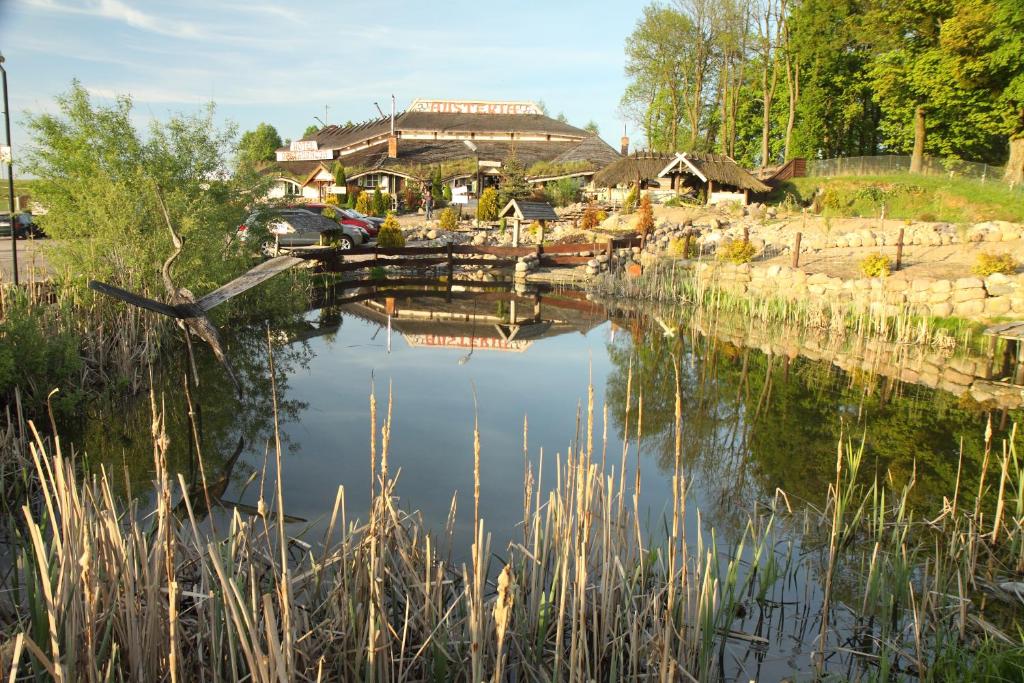 a pond with a house in the background at Austeria in Ostróda