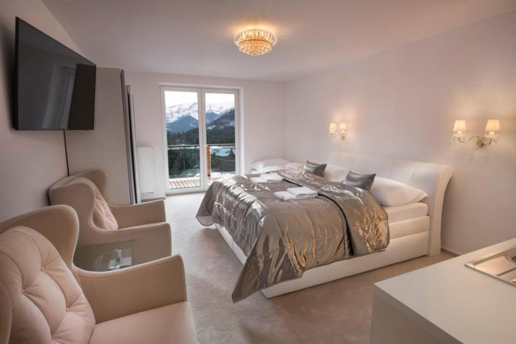 a bedroom with a bed and a couch and a tv at Apartmany U Jezka in Ždiar