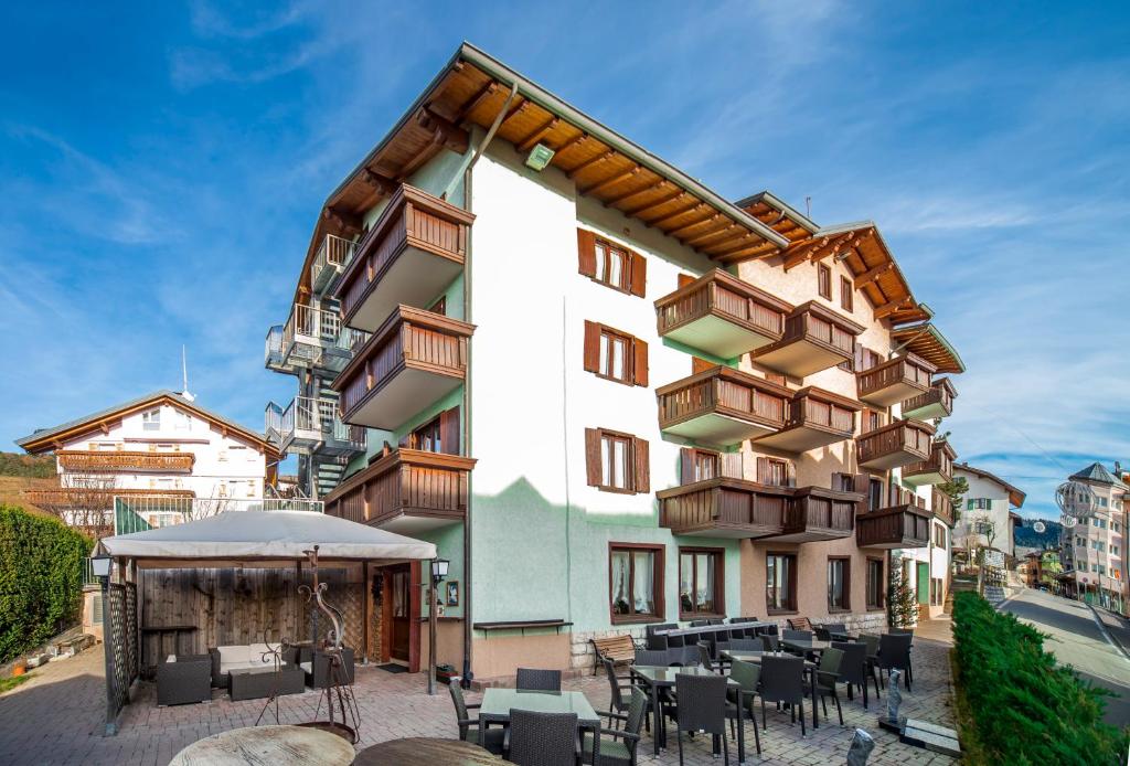 un bâtiment avec des tables et des chaises devant lui dans l'établissement Hotel Irma, à Folgaria