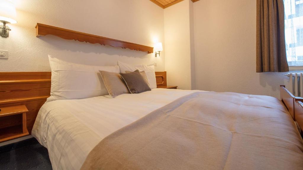 a bedroom with a large white bed with two pillows at Alpenblick in Zermatt