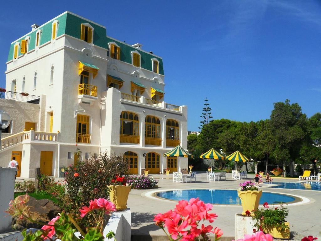 ein großes weißes Gebäude mit einem Pool davor in der Unterkunft Hôtel LES MIMOSAS TABARKA in Tabarca