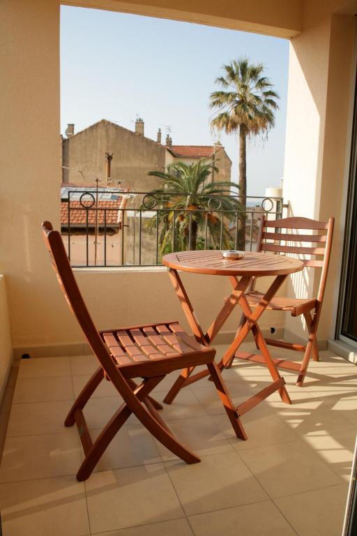 d'une table et d'une chaise sur un balcon avec un palmier dans l'établissement Le Vieux Port Apartments, à Cannes
