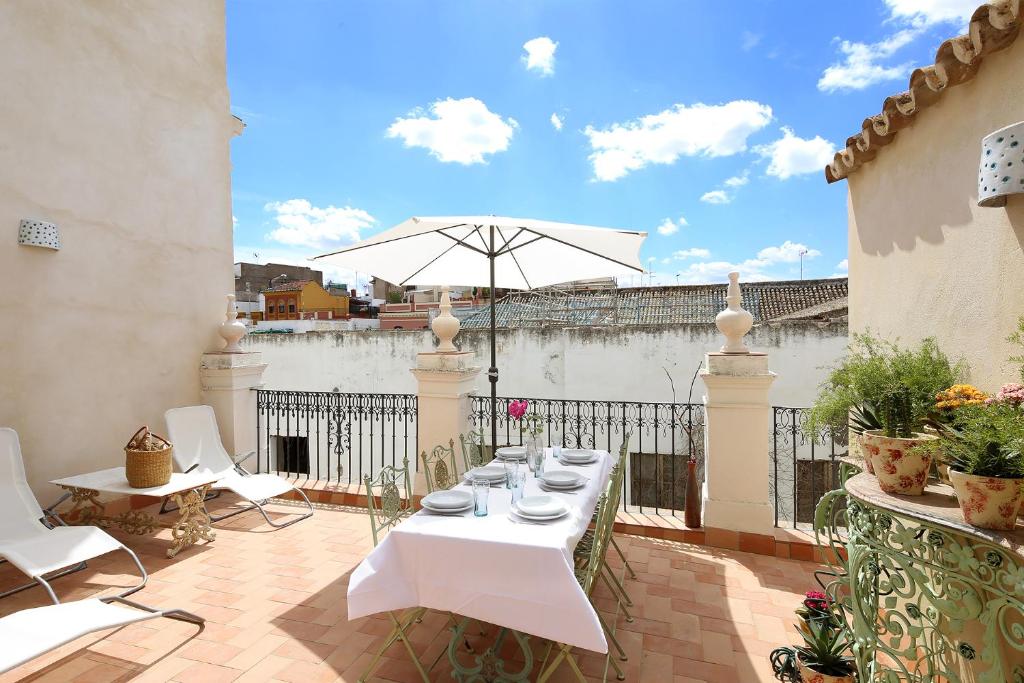 una mesa blanca y sillas en un balcón con sombrilla en Veoapartment Quintana Terrace, en Sevilla