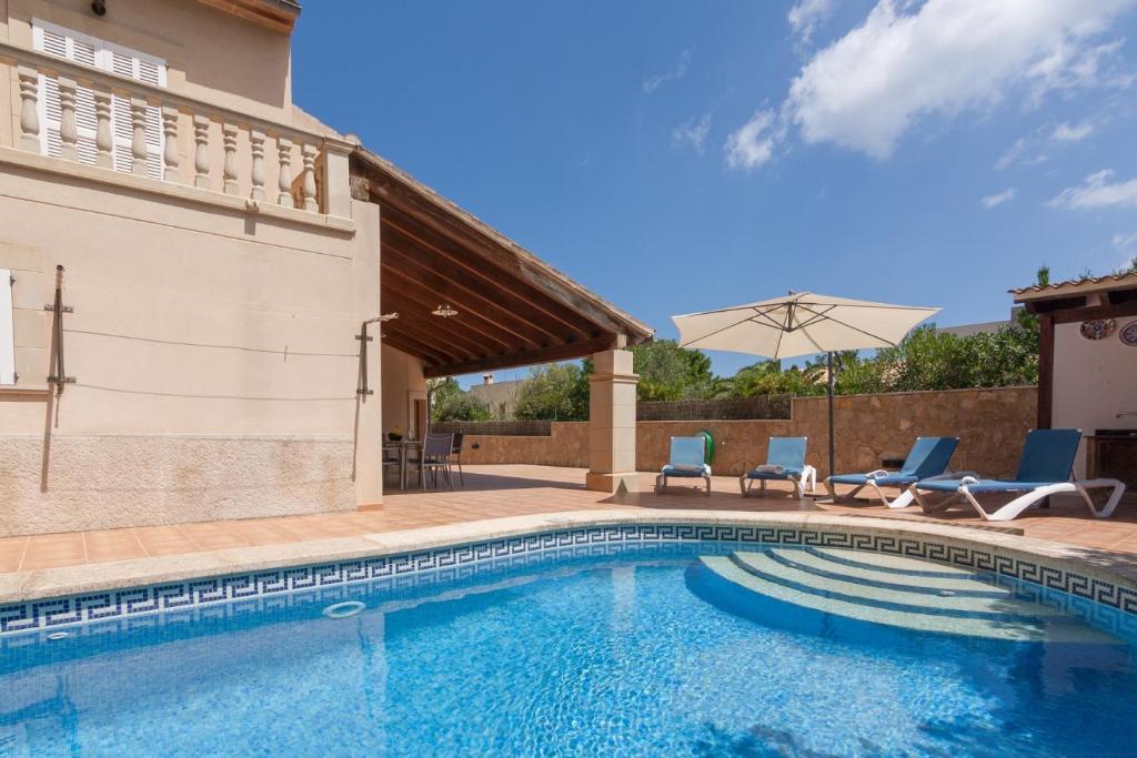 a pool with chairs and an umbrella next to a house at Montferrutx in Colonia de Sant Pere