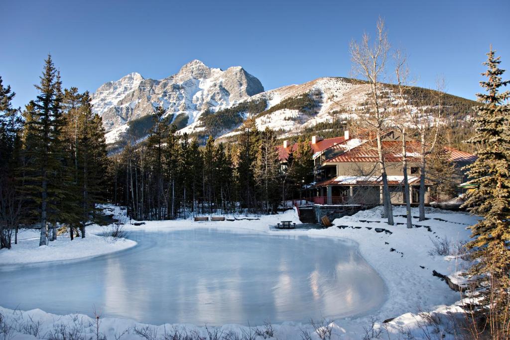 a pond in the snow with a mountain in the background at Crosswaters Resort at Kananaskis in Kananaskis Village