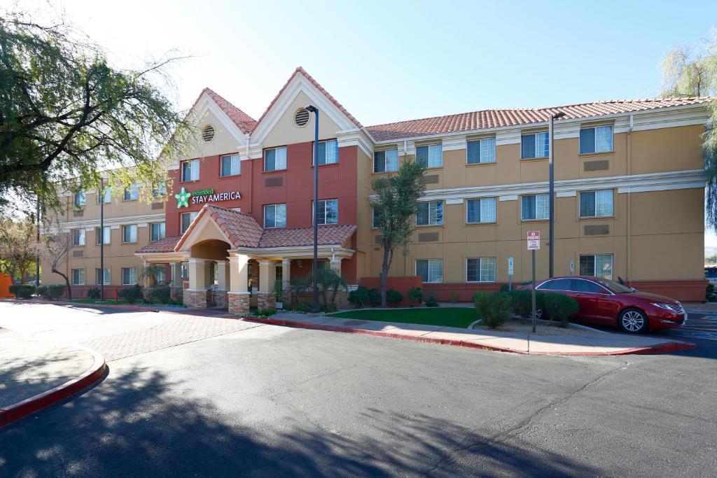 un hotel con un coche rojo estacionado frente a él en Extended Stay America Suites - Phoenix - Airport - Tempe, en Tempe