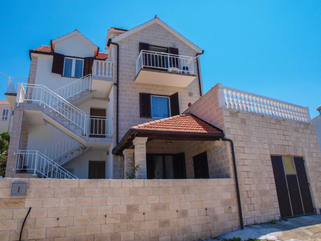 a large white building with a brick wall at Apartments Vukovic in Postira