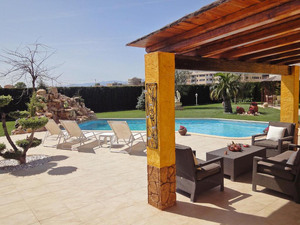 eine Terrasse mit Stühlen und einem Pool in der Unterkunft Holiday Home L'Aldea by Interhome in L'Aldea